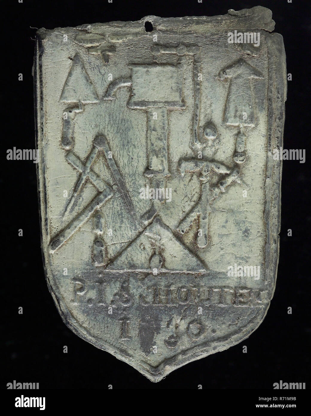 P.I. Schouten, Roof bonnet, shield-shaped cover plate with P.I. Schouten and various leader tools, bollard lead mark lead metal, Roof bonnet shield-shaped cover of the nails with embossed year that can not be deciphered and the name of the plumber P.I. Schouten and above slide tool tools on plate: P.I. Schouten 1 ?? 0 lead Stock Photo