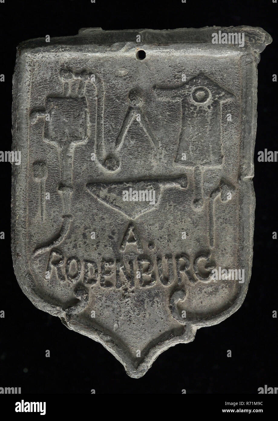 A. Rodenburg, Roof bonnet, shield-shaped cover plate with . Rodenburg and various guide tools, Barrier lead hallmark metal lead, Roof bonnet shield-shaped cover plate of the nails with the name of the plumber . Rodenburg and above it various guide tools, . RODENBURG. leader Stock Photo