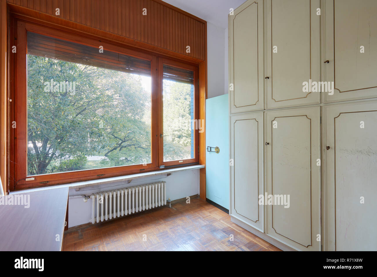 Room with wardrobe and large window, apartment interior in old house with garden Stock Photo