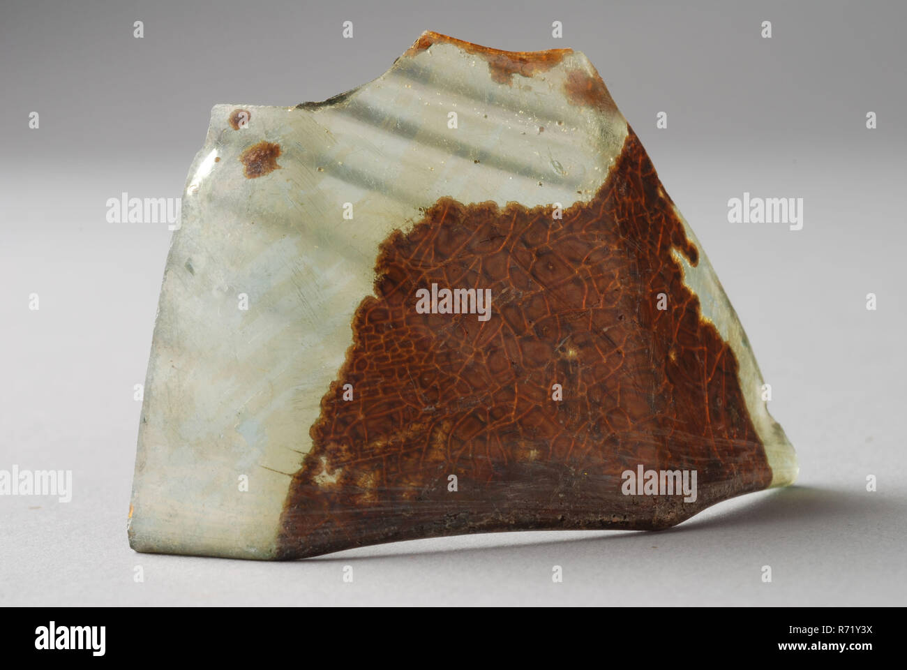 Fragment of wall and edge of octagonal pipe glass, drinking glass drinking utensils tableware holder soil find glass forest glass, free blown and shaped into blown Fragment of wall and edge of octagonal pipe glass in clear light green glass (forest glass). The wall has diagonally upwardly ribbed pattern of imposed and blown glass threads. octagonal shape is formed during manufacture by inserted octagonal (usually ceramic) mold. The edge is slightly thickened by fusion and has wavy line between the angles archeology underground pit Rotterdam City Triangle Groenendaal archaeological find in the  Stock Photo