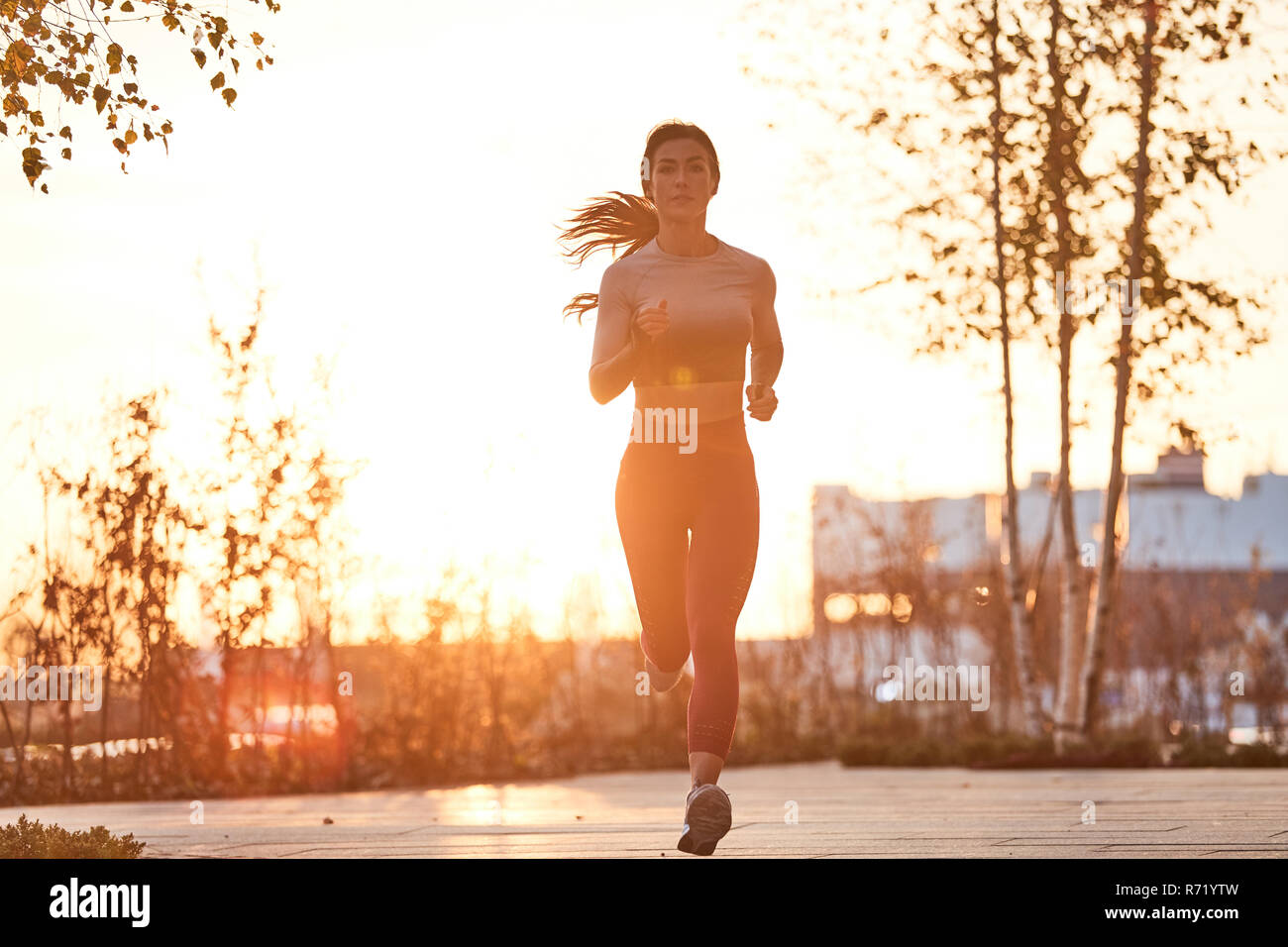 Single Caucasian Female jogging in a city centre at sunset Stock Photo