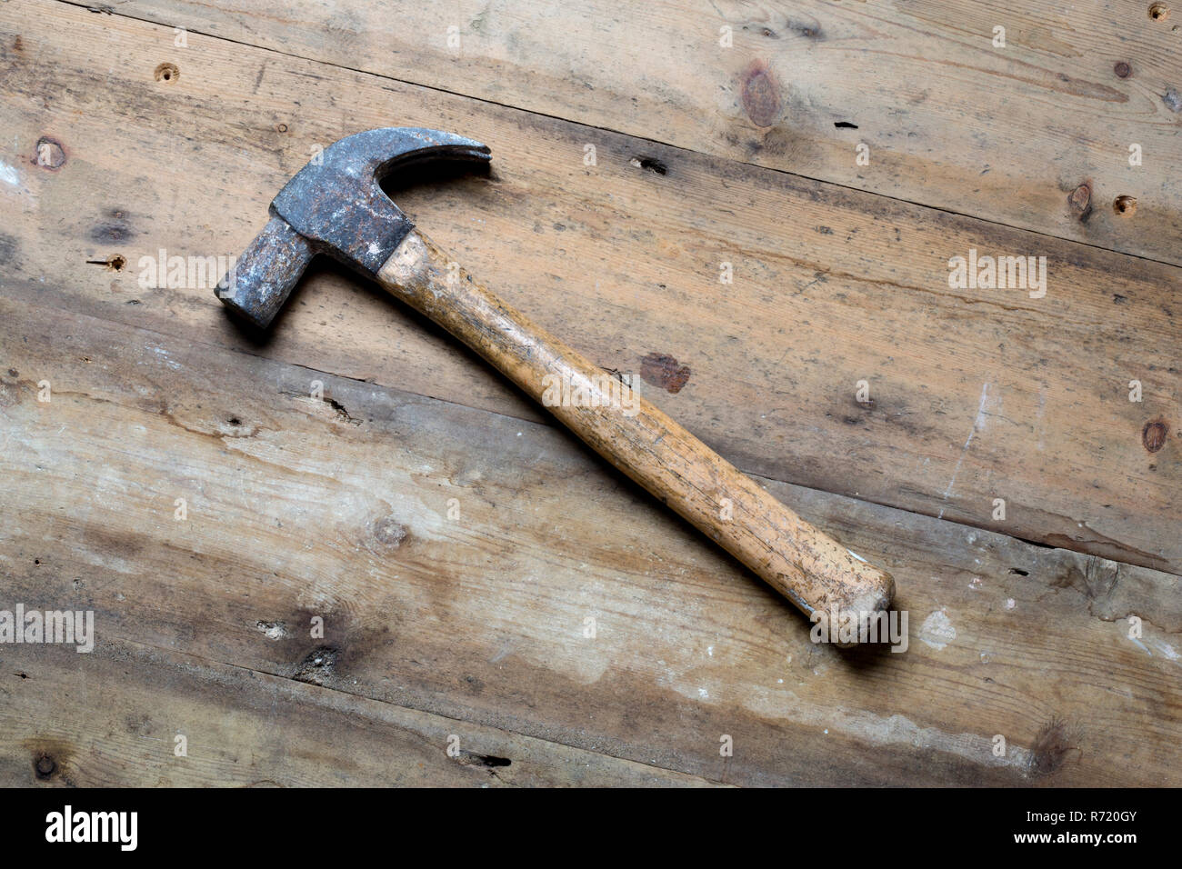 A wooden handled claw hammer on a rough wood surface. Stock Photo