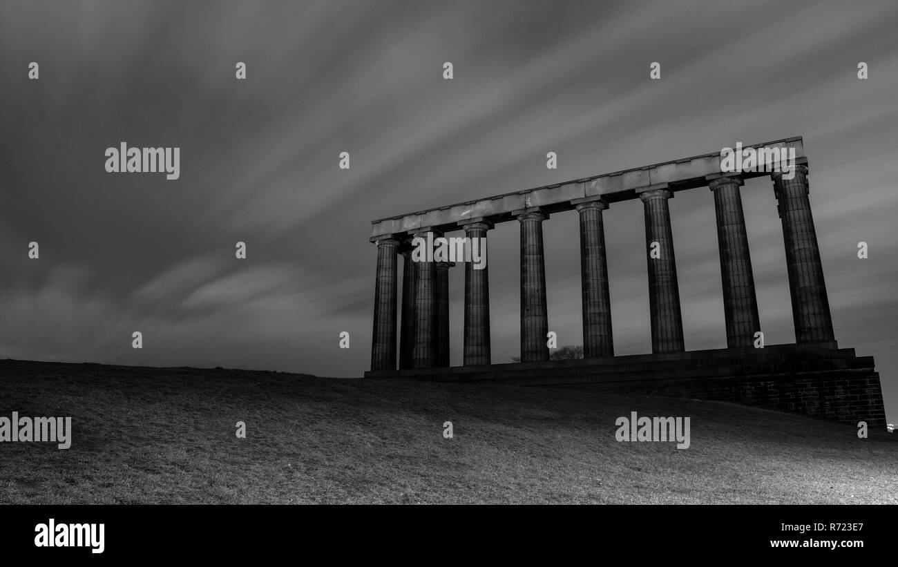 Clouds are blown across the abandoned National Monument of Scotland at night in a long-exposure photograph of Calton Hill in Edinburgh. Stock Photo
