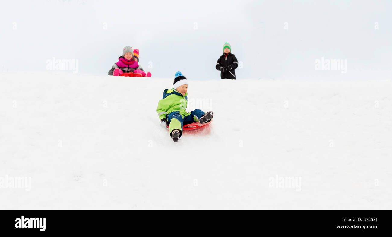 kids sliding on sleds down snow hill in winter Stock Photo Alamy