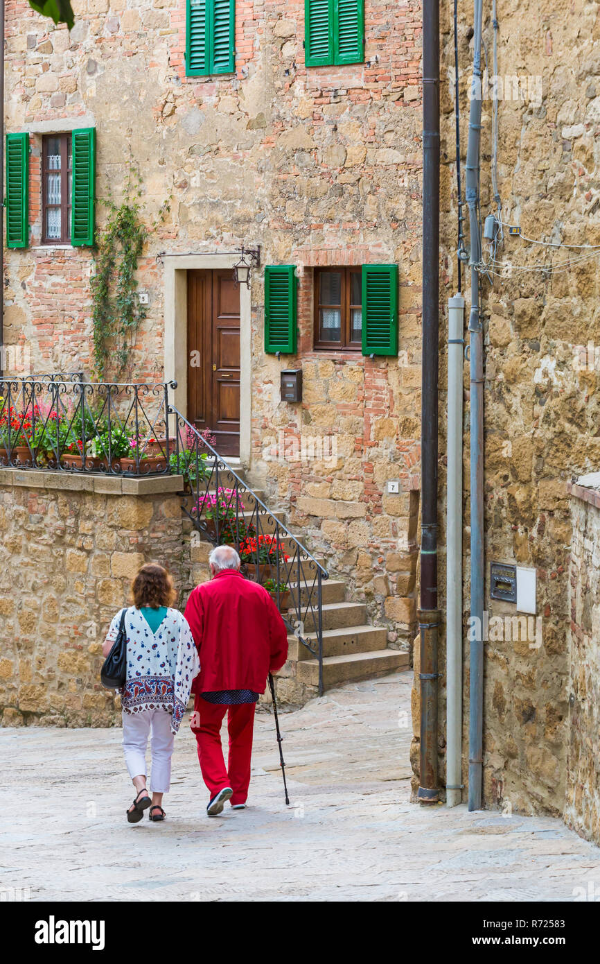 Man and woman walking down street in medieval village town of Monticchiello, near Pienza, Tuscany, Italy in May Stock Photo