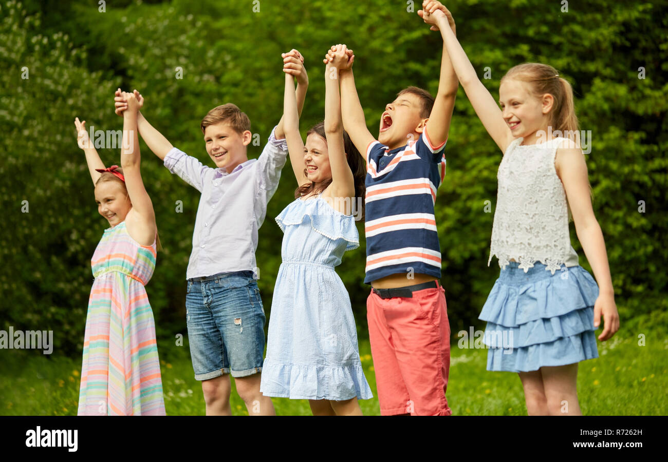 happy kids holding raised hands in summer park Stock Photo - Alamy