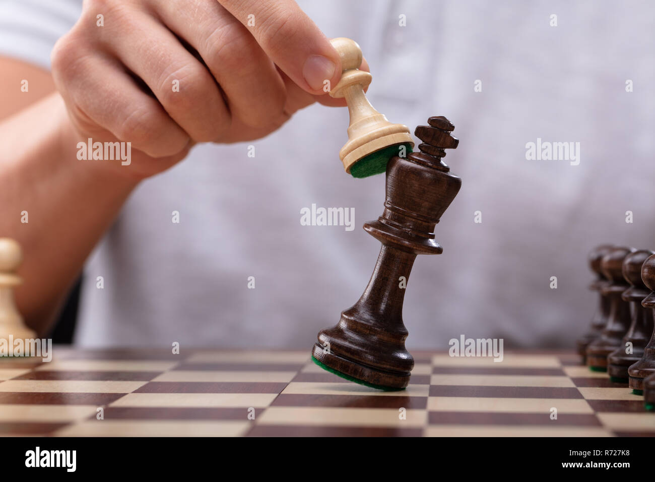 Close-up Of A Man's Hand Defeating King Chess Piece With Pawn Stock Photo