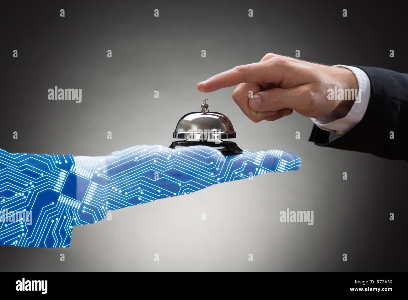 Businessperson's Hand Ringing Service Bell Held By Digital Generated Human Hand On Grey Background Stock Photo