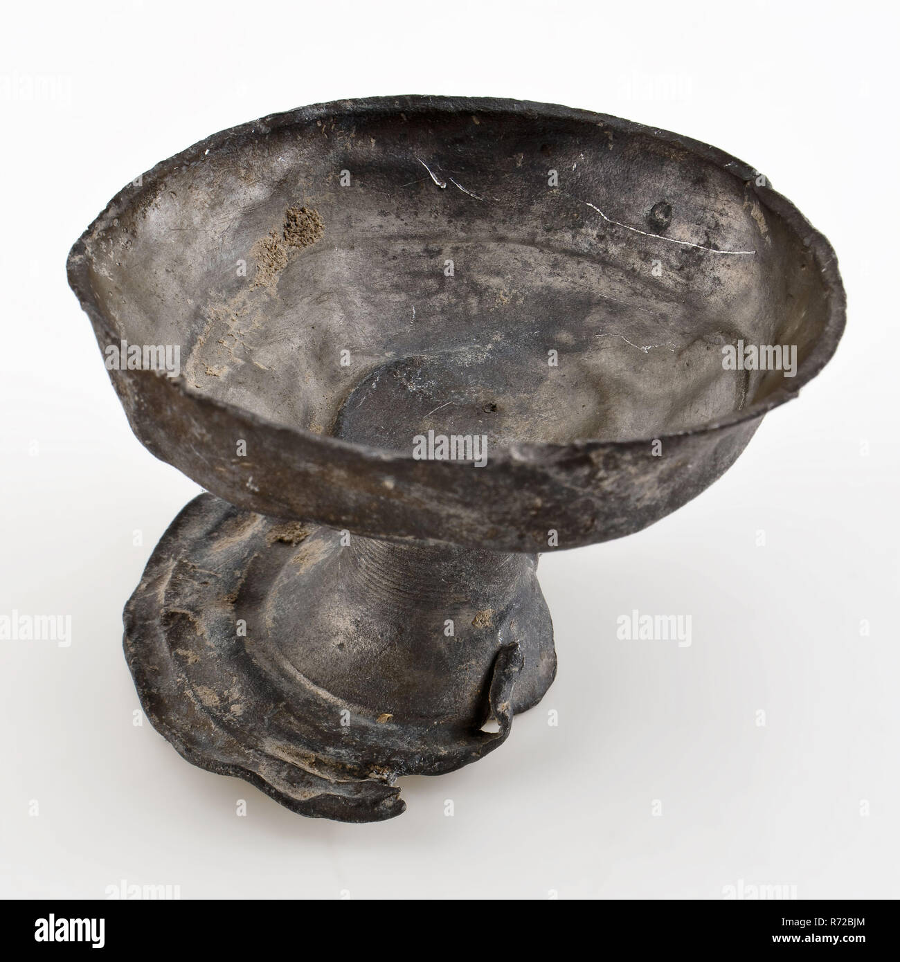 Pewter stacking cup on stand, cup holder soil find tin metal, cast pewter cup on base. Tin holder in the shape of chalice with raised edge Unnoticed archeology Rotterdam rail tunnel drink serving inn archaeological find in the soil Rail Tunnel. Stock Photo