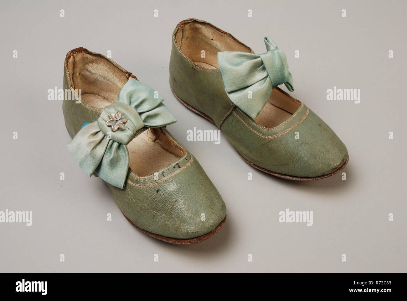 Mint green leather children s shoes with instep strap on which satin bow with decorative button strap has button closure on the side shoe footwear children s clothing clothing leather satin metal text...