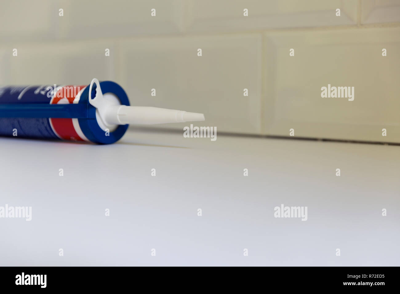 Plumber applying silicone sealant to the countertop and ceramic tile