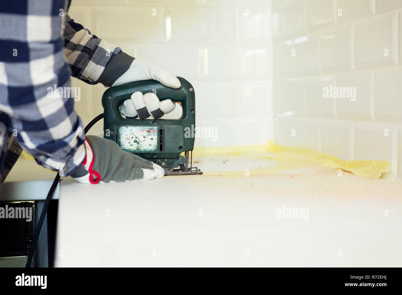 Man cutting kitchen countertop using electric jigsaw. Home improvement