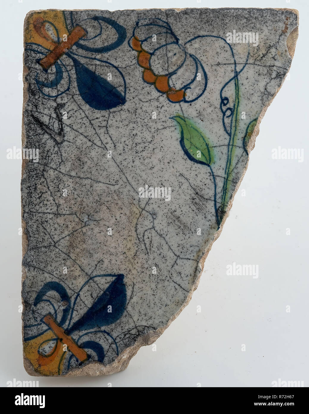 Fragment flower tile with corner decoration and central multi-colored flower arrangement, corner pattern lily, wall tile tile visualization earth discovery ceramics earthenware glaze tin glazing, baked 2x glazed painted Orange green and blue on white archeology Rotterdam rail tunnel Soil discovery: rail tunnel Rotterdam. Stock Photo