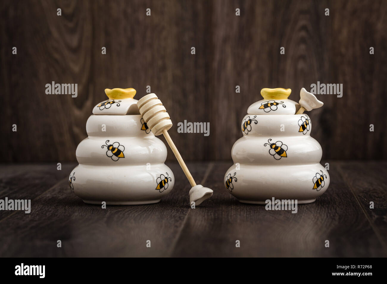 Ceramic Honey Pots with Wooden Dipper on Brown Background Stock Photo