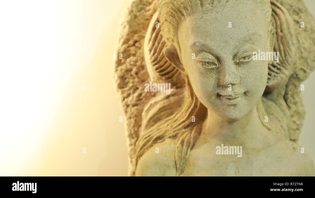closeup of illuminated angel statue face with light, white background Stock Photo