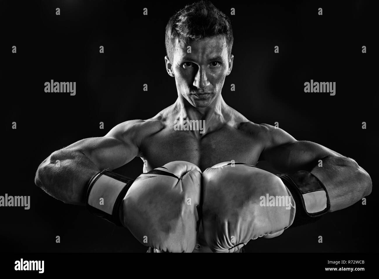 Man in boxing gloves on dark background. Boxer sportsman before fight