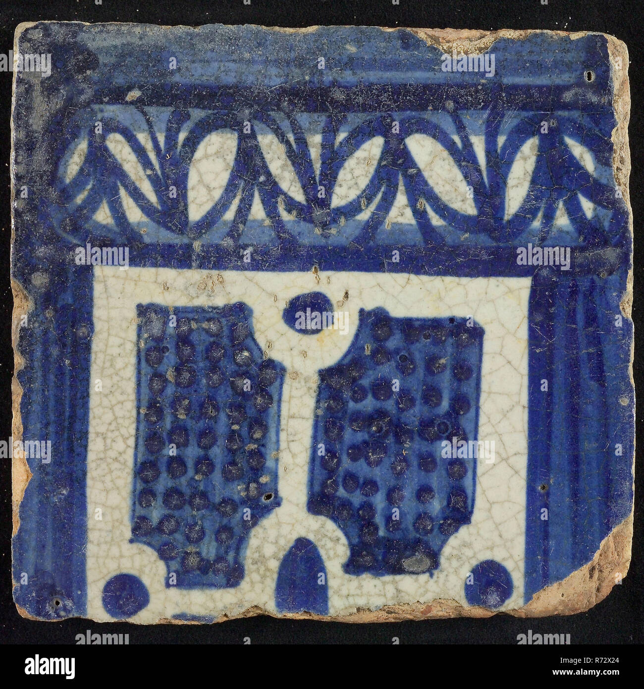 Tile of chimney pilaster, blue on white, bottom of column with basement with leaf motif, compartment with dots, chimney pilaster tile pellet image fragment ceramic earthenware glaze, baked 2x glazed painted Tile part of chimney pilaster originally twelve or thirteen high Rony shard square two nail holes. Blue on white fond. Tile forms part of single-row pilaster in Renaissance style and shows the underside of column with division with dark blue dots on the blue background. on Rotterdam in May 1940. Stock Photo