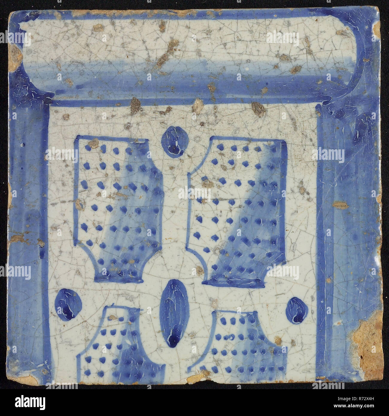 Tile of chimney pilaster, blue on white, bottom of column with basement, compartment with dots, chimney pilaster tile pilaster footage fragment ceramic earthenware glaze, baked 2x glazed painted Tile part of chimney pilaster originally twelve or thirteen high Yellow shard square two nail holes. Blue on white fond. Tile is part of single-row pilaster in Renaissance style and shows the underside of column with division with blue dots Shadow on the right On center square: G 1914 construction city hall Zandstraat-quarters Second World War war bombardment Rotterdam City Center Stadsdriehoek 1940 re Stock Photo