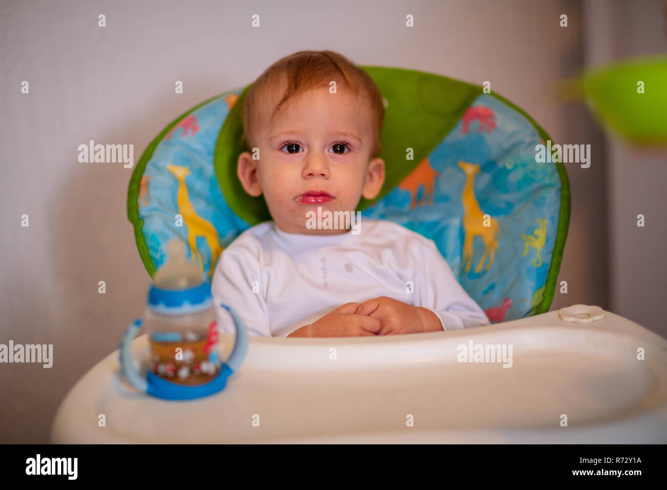 Little Kid Boy Sitting In Chair For Feeding And Drinking