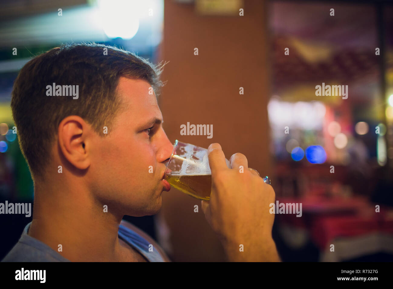 Man drinking beer. Side view of handsome young man drinking beer while