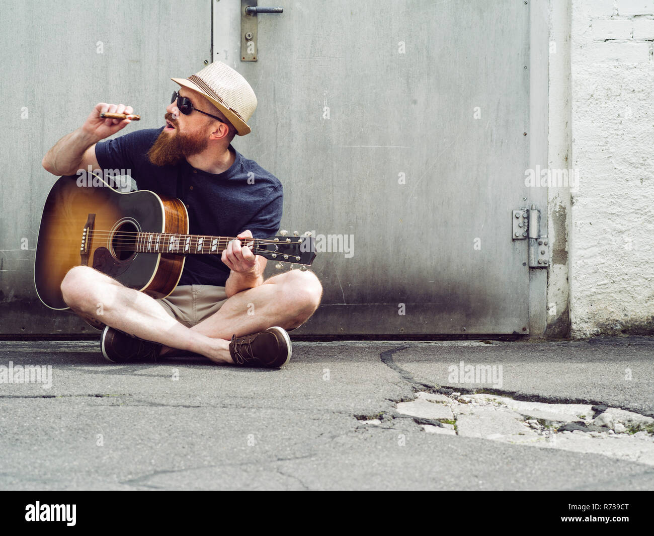 Bearded man playing acoustic guitar and smoking cigar Stock Photo