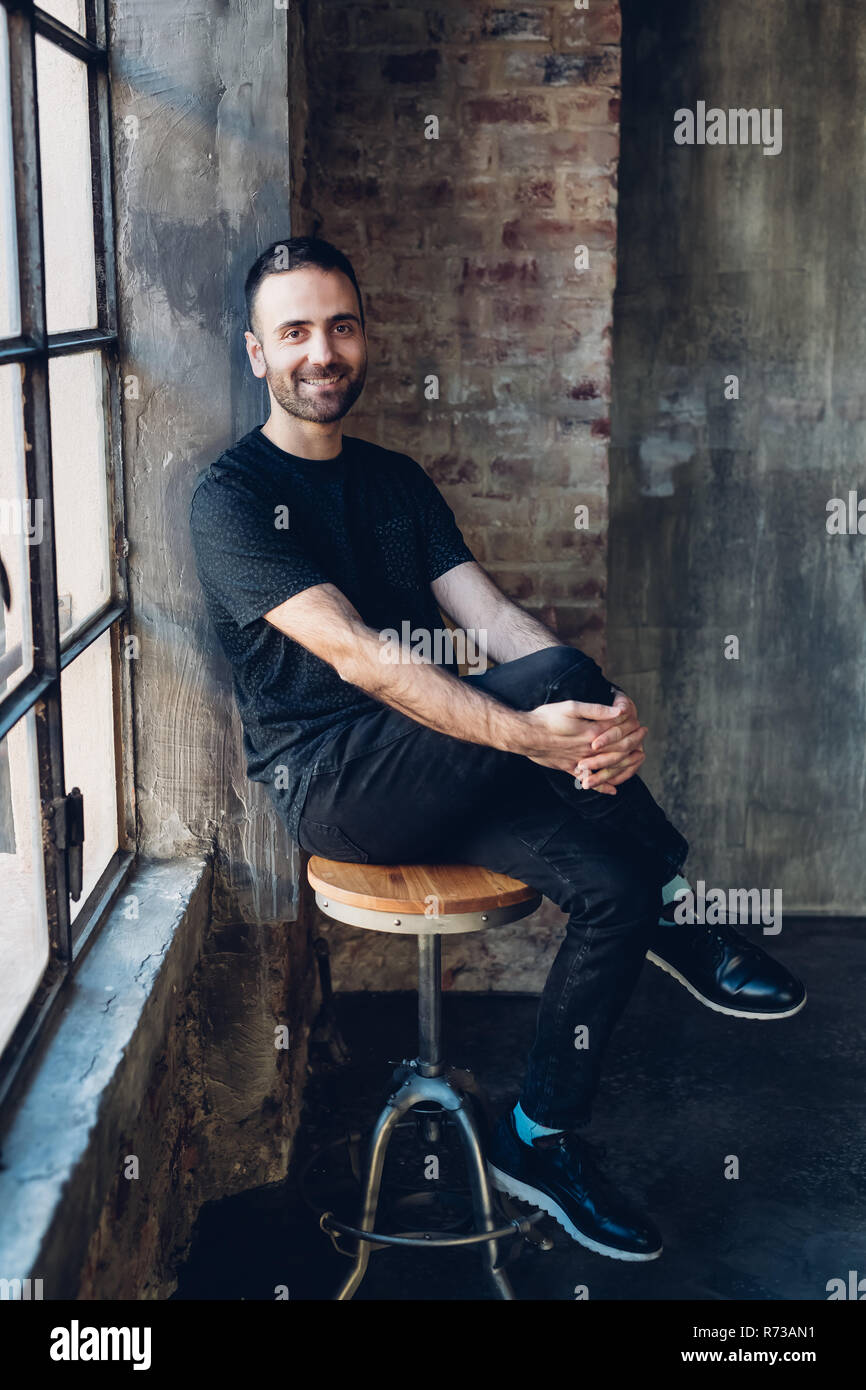 Man sitting on swivel stool by window Stock Photo