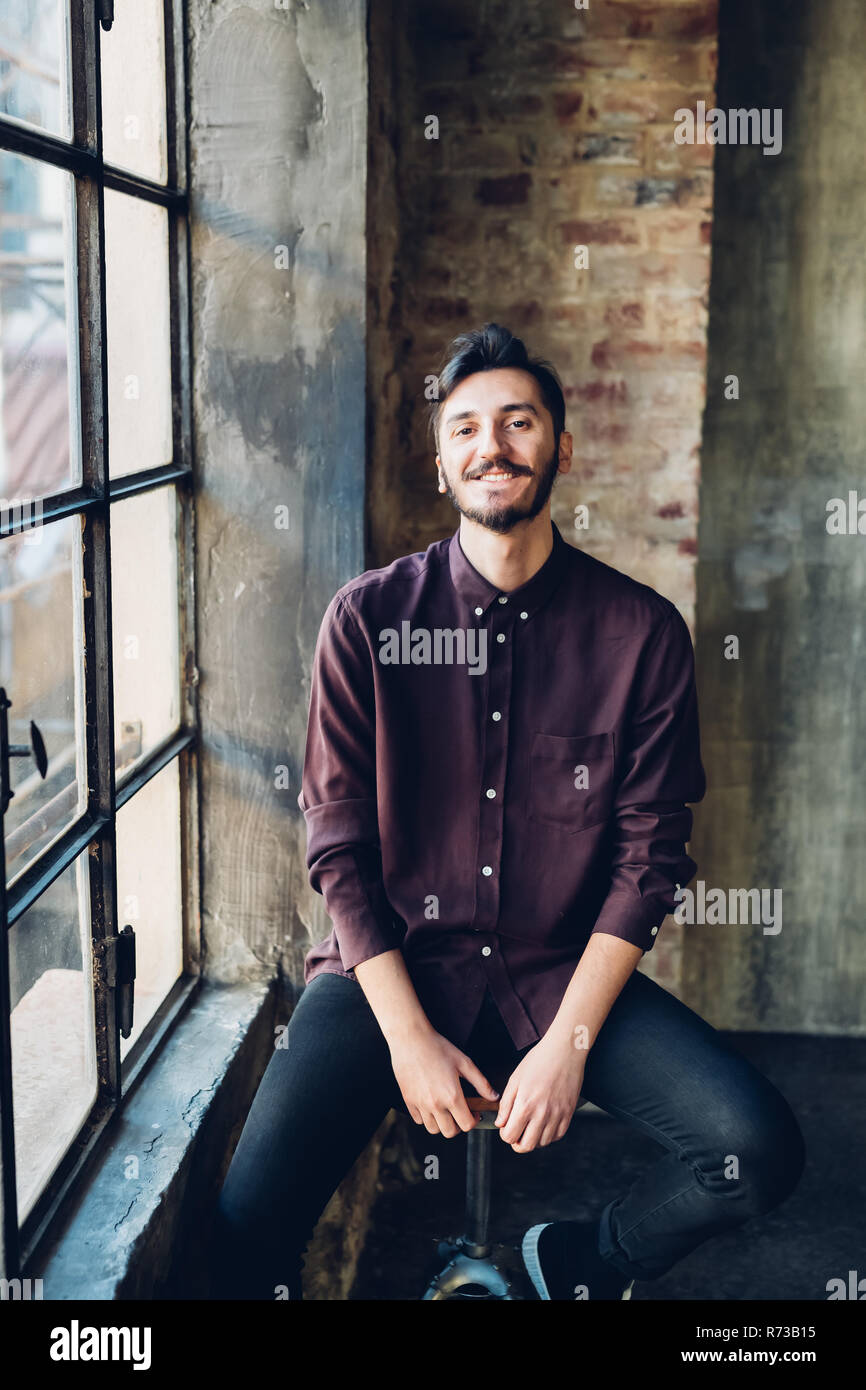 Man sitting on swivel stool by window Stock Photo