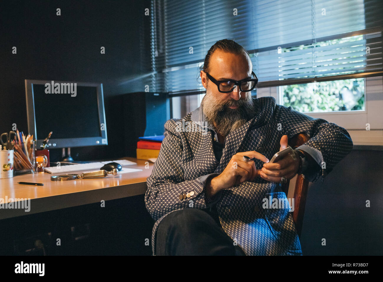Man using cellphone at desk Stock Photo