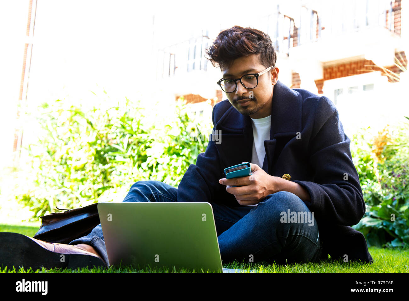 Businessman using smartphone and laptop on grass Stock Photo