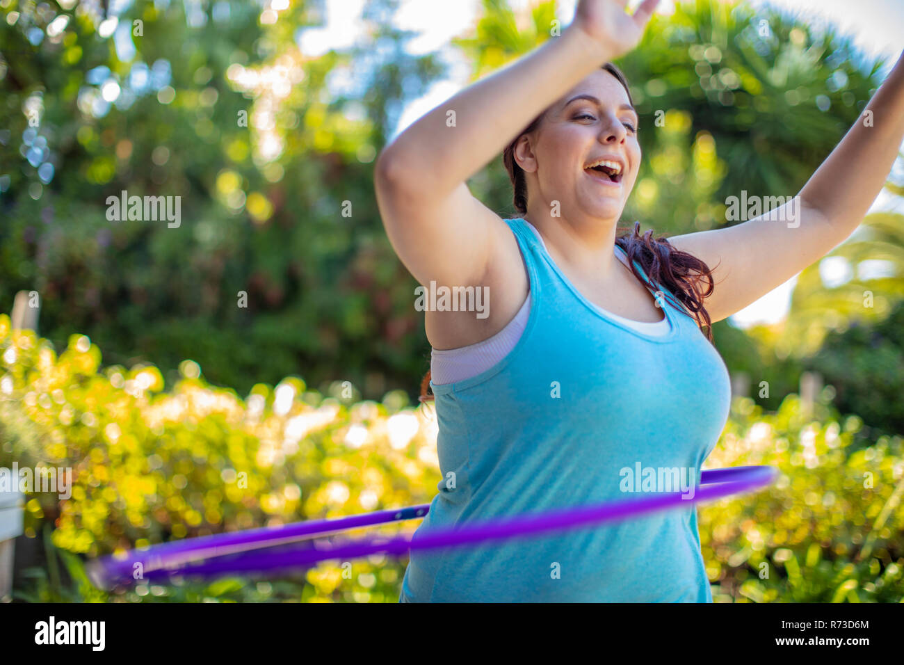 Woman exercising with hula hoop in garden Stock Photo