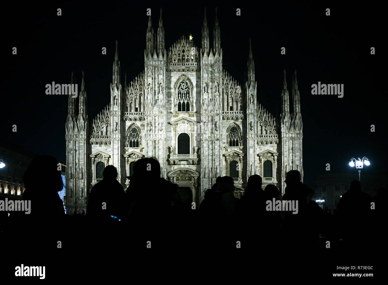 Christmas in Milan, Italy. Silhouette of people in front of the Duomo cathedral facade illuminated at night. Stock Photo