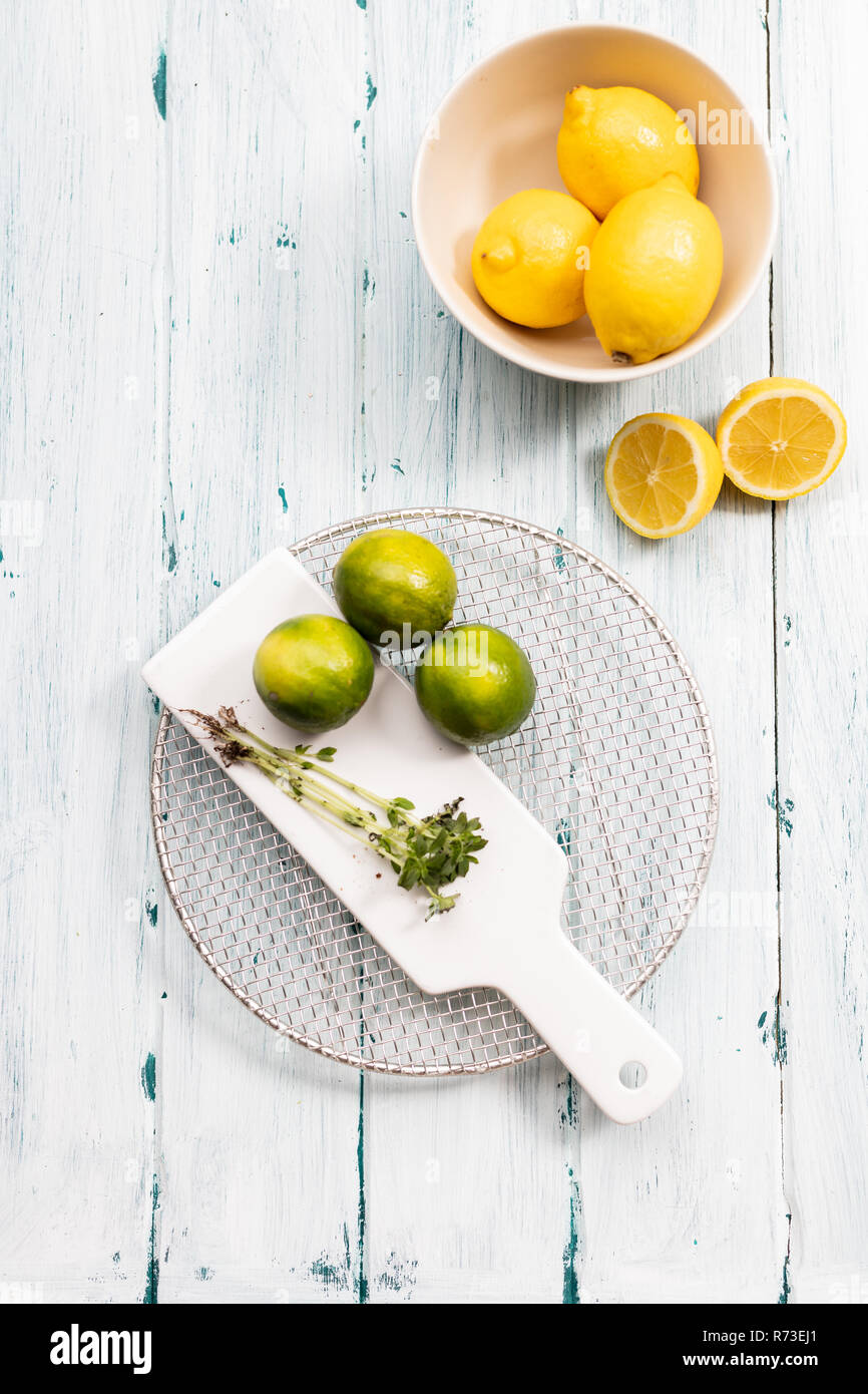 Bowl of lemons with limes on chopping board, still life, overhead view