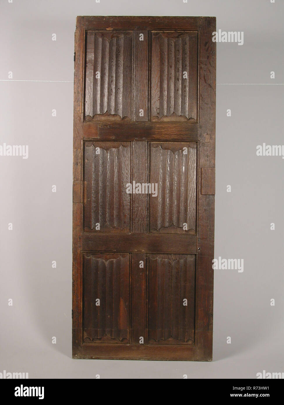 Room door with letter panels, door building part oak wood, sawn planed chiselled Gothic room door with six letter panels: decorated with vertical on top and bottom serrated hollow scalloped folds The styles and lines in which the panels are located with dowels put together close living environment interior Gothic Stock Photo