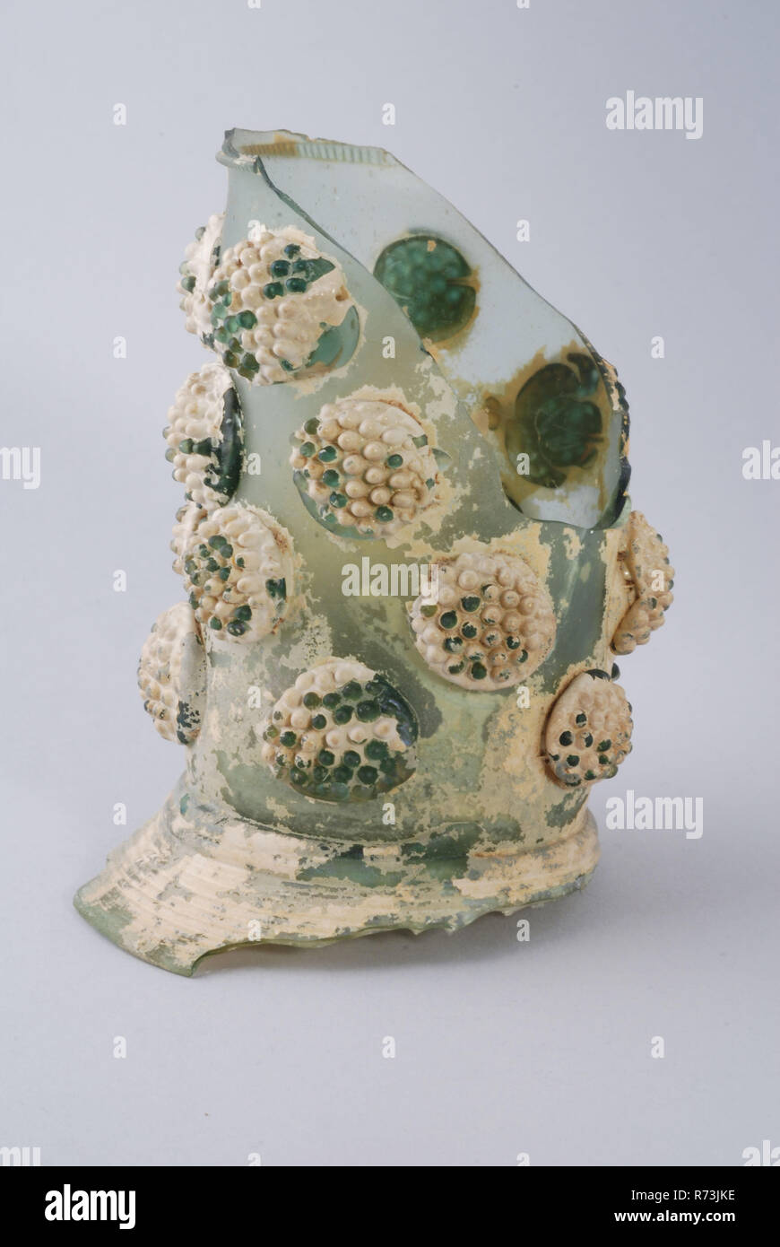 Fragment of soil and stem of roemer, roemer wineglass drinking glass drinking utensils tableware holder soil find glass forest glass, free blown and formed glass application Fragment of foot bottom part of trunk and starter part chalice of roemer in clear light green glass (forest glass ) Upright foot of twelve round wound glass wire. Pontil mark under pointed soil (fracture across). Straight hollow stem (dm 6.0 cm) open to calyx with four rows of five prominent bramble buds, one of which is missing. Ribbed round wound glass wire at the transition of stem and calyx. Some incitement of chalice  Stock Photo