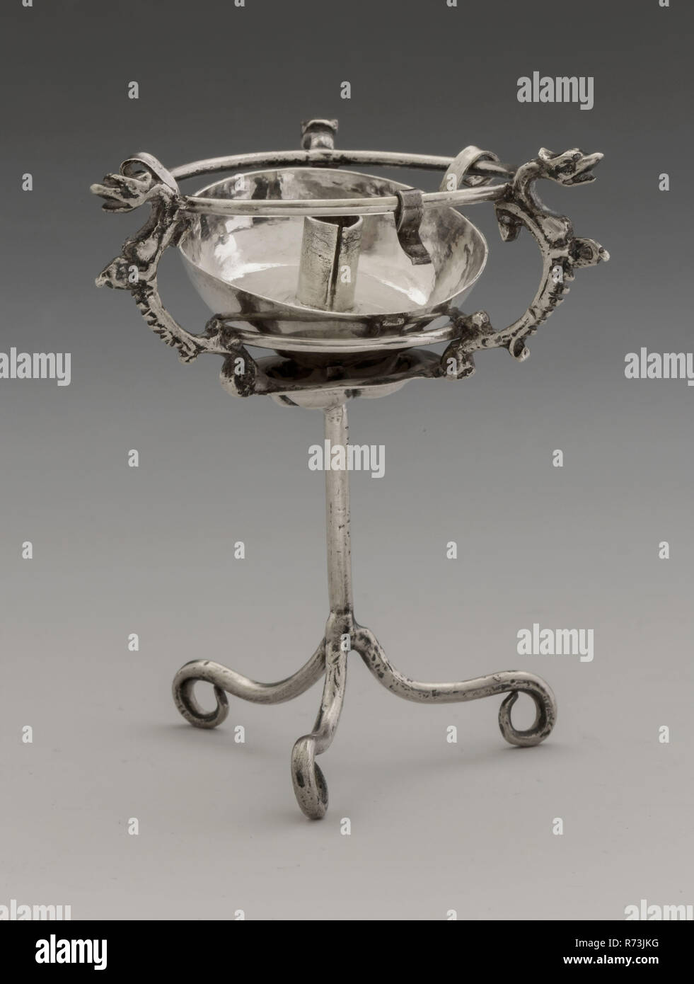 Silver miniature sconce with stand, sconce dolls toy relaxant miniature model silver, Round sconce with three hooks hanging on stand; standard consists of two rings and receptacle that are connected to each other by three volutes with dragon's head. This whole stands on stem that ends in three volute-shaped paws to decorate illuminate home interior Stock Photo