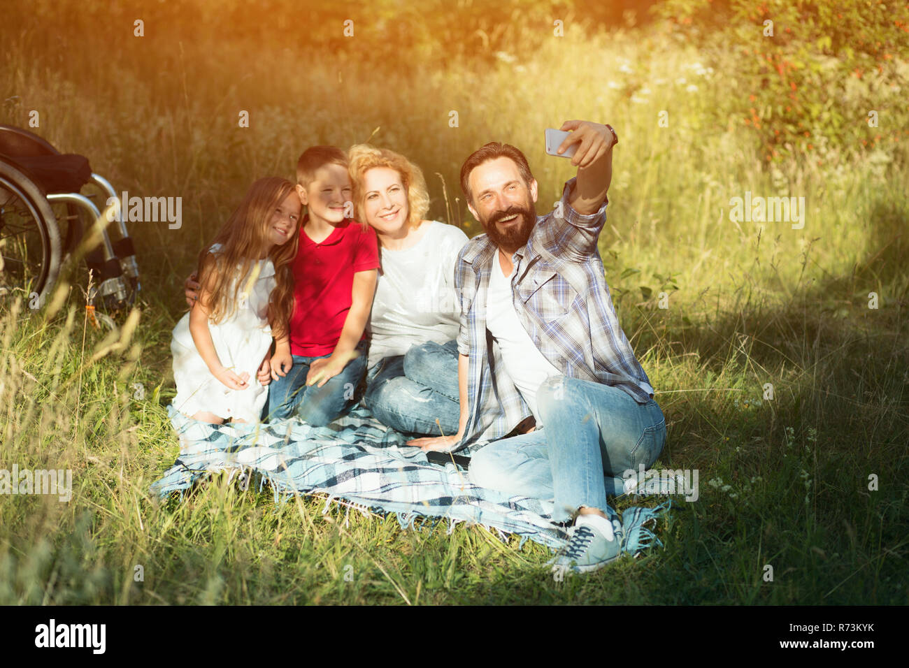 Happy family taking selfie on the picnic in park. Paraplegic Stock Photo