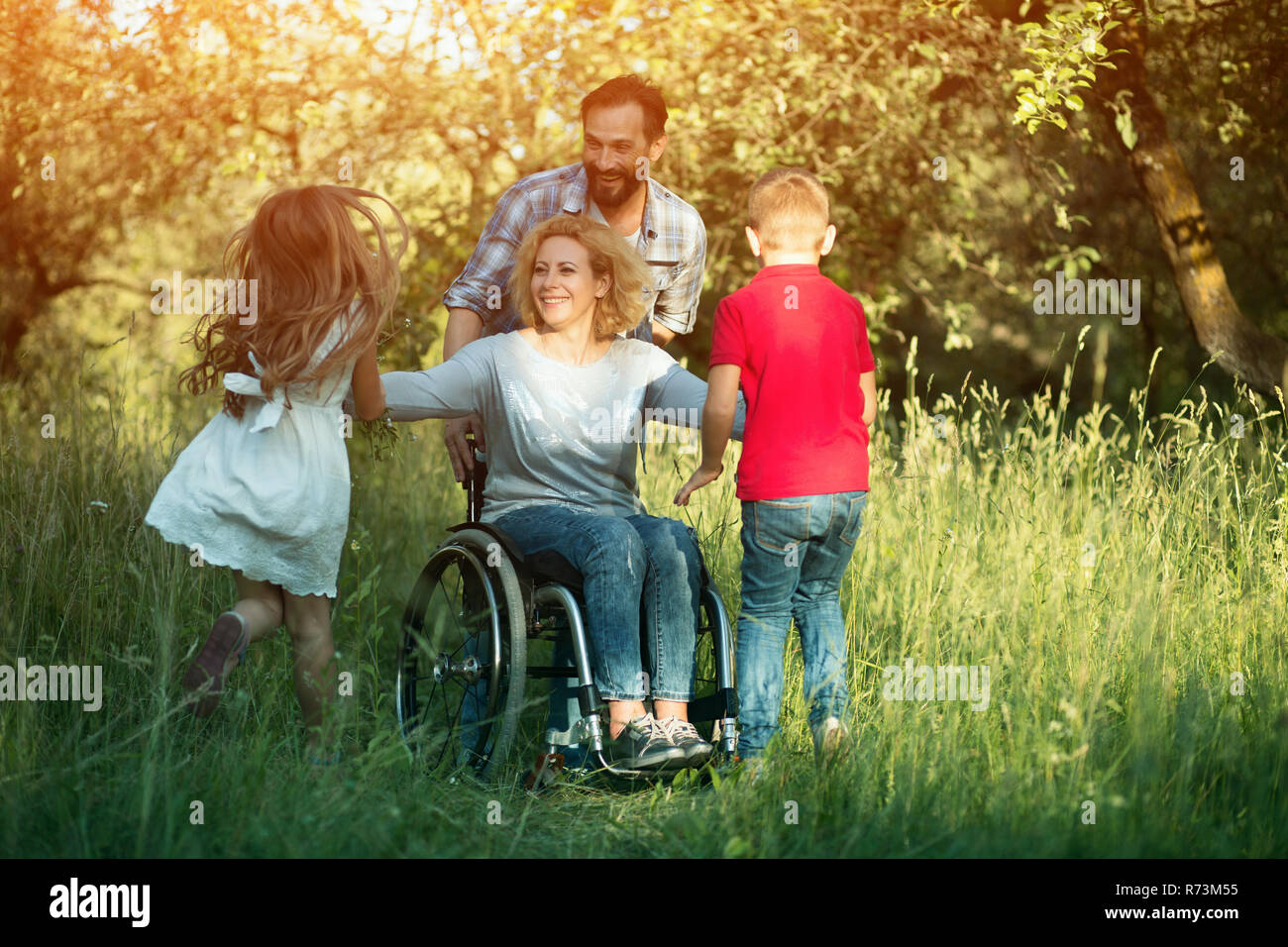 Children run to their disabled mother in the park Stock Photo