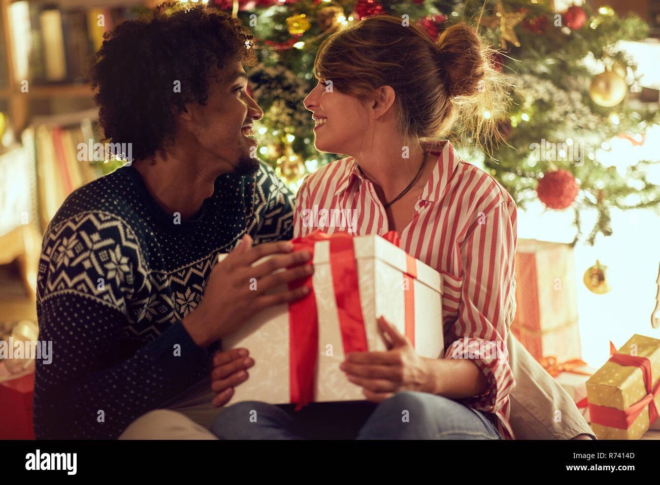 Romantic male and female exchanging Christmas presents and enjoying in ...
