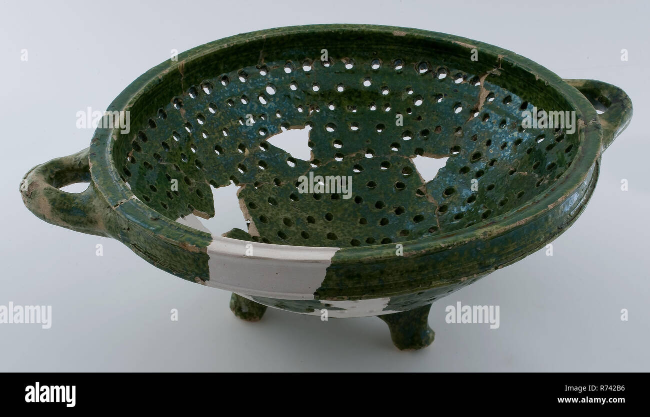 Green tapering colander on three legs, with two lying sausage ears, colander kitchen utensils earthenware ceramics earthenware glaze lead glaze, hand-twisted glazed baked Pottery colander on three legs. White shard green and completely glazed Deep and bowl-shaped colander with two lying sausage ears attached to the rim. Partially restored Restoration is blank archeology Rotterdam City triangle New port indigenous pottery draining food preparation cooking kitchen Soil discovery Rotterdam Nieuwe Haven 1st cesspool (around) 21-08-1980 Stock Photo