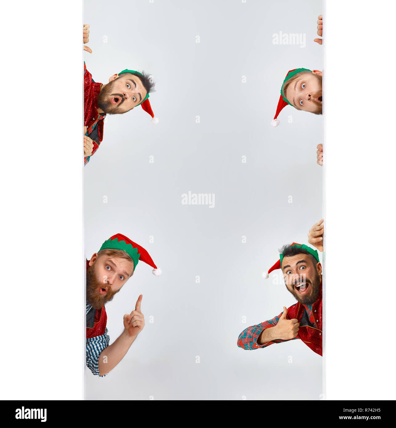 The happy smiling surprised friendly men dressed like a funny gnome or elf posing on an isolated gray studio background. The winter, holiday, christmas concept Stock Photo