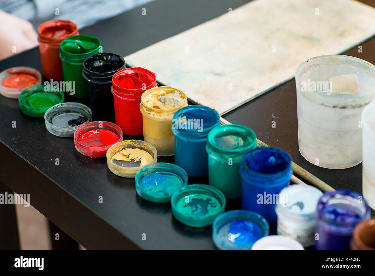 Paints and brushes are on the table on the palette. Workplace artist lover or child. Stock Photo