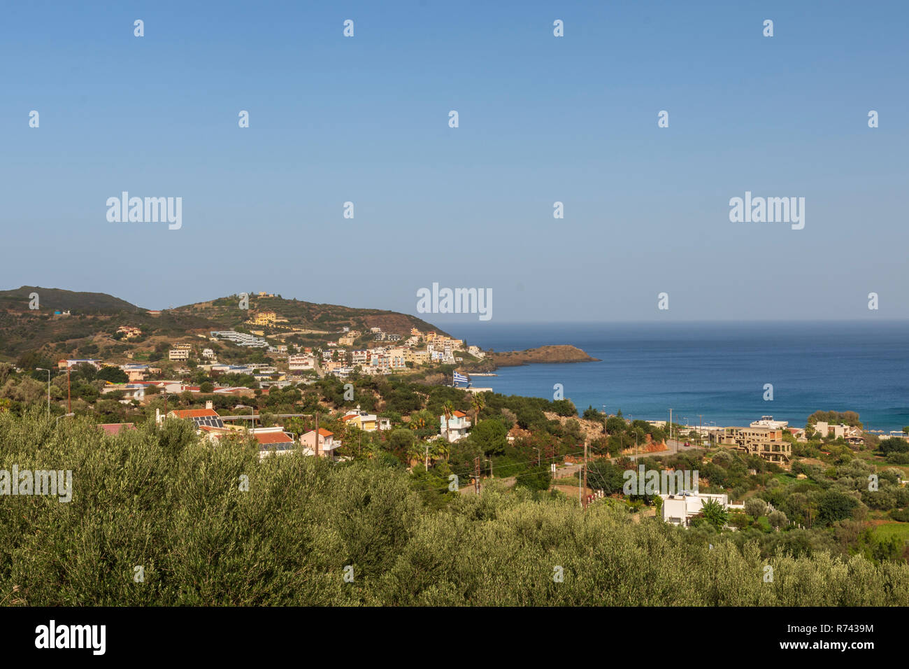 View to the Nortwest over the Bali area in Rethymno on Crete Island with som bushes in foreground and a blue sky in background. Stock Photo