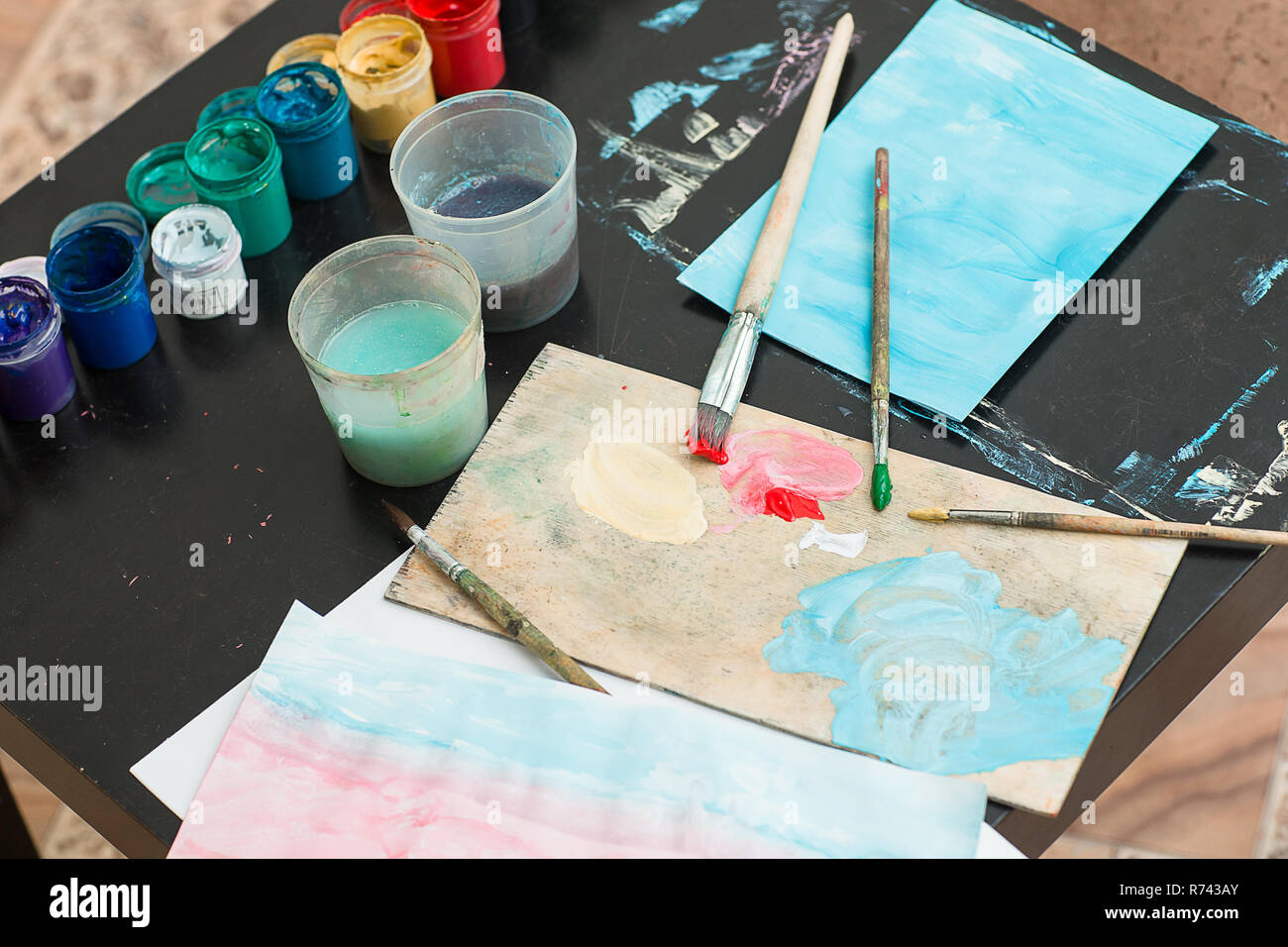 Paints and brushes are on the table on the palette. Workplace artist lover or child. Stock Photo