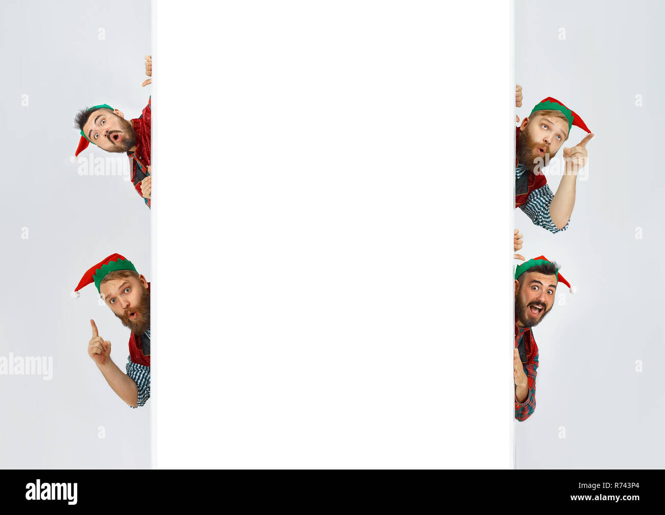 The happy smiling surprised friendly men dressed like a funny gnome or elf posing on an isolated gray studio background. The winter, holiday, christmas concept Stock Photo