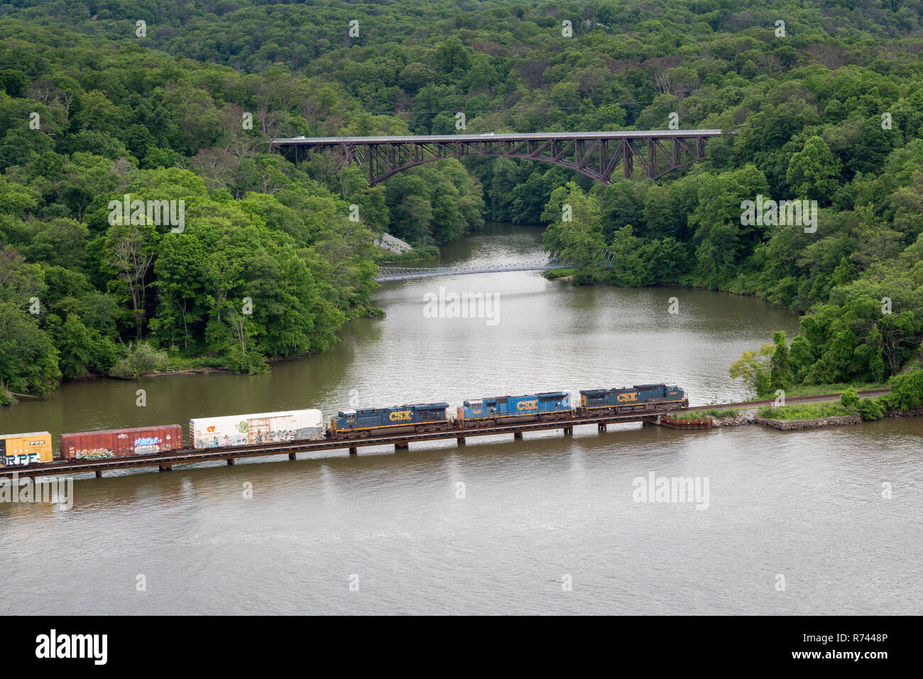 A freight train crossing over Popolopen Creek as it feeds into the Hudson River below a hiking trail and Highway 9W. Bear Mountain Bridge, New York Stock Photo