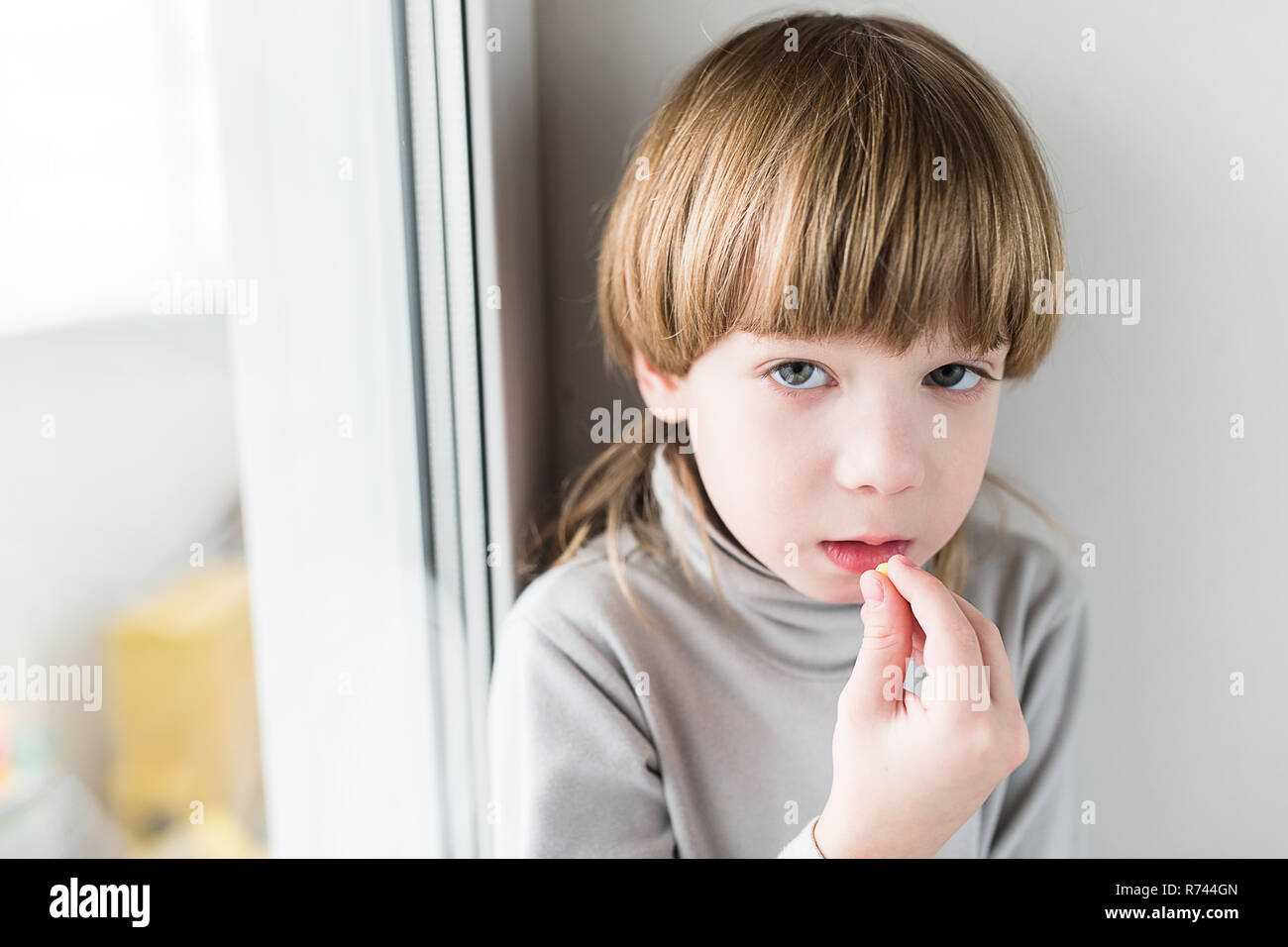 Little blonde boy taking drugs and take vitamins Stock Photo
