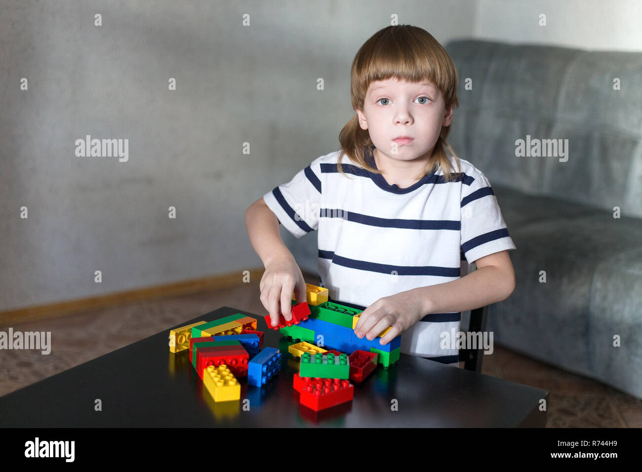 Little kid boy playing with lots of colorful plastic blocks indoor ...