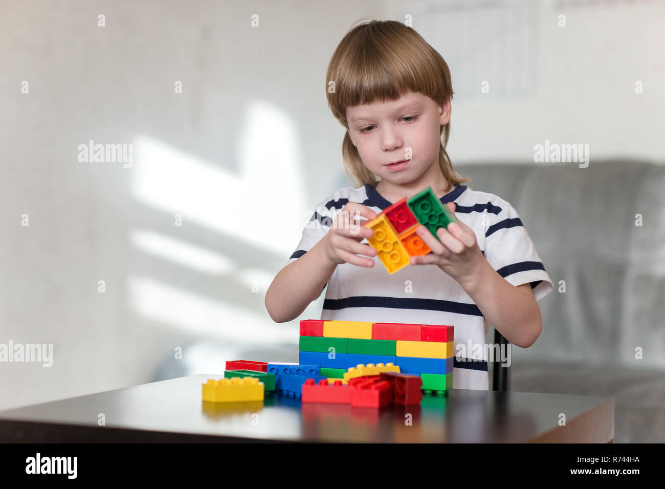 Little kid boy playing with lots of colorful plastic blocks indoor ...
