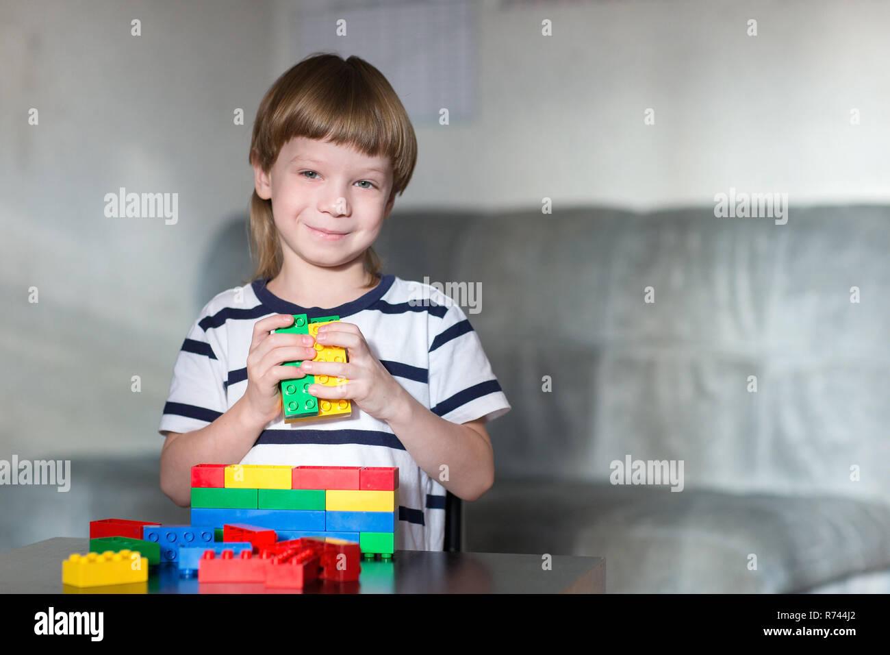 Little kid boy playing with lots of colorful plastic blocks indoor ...