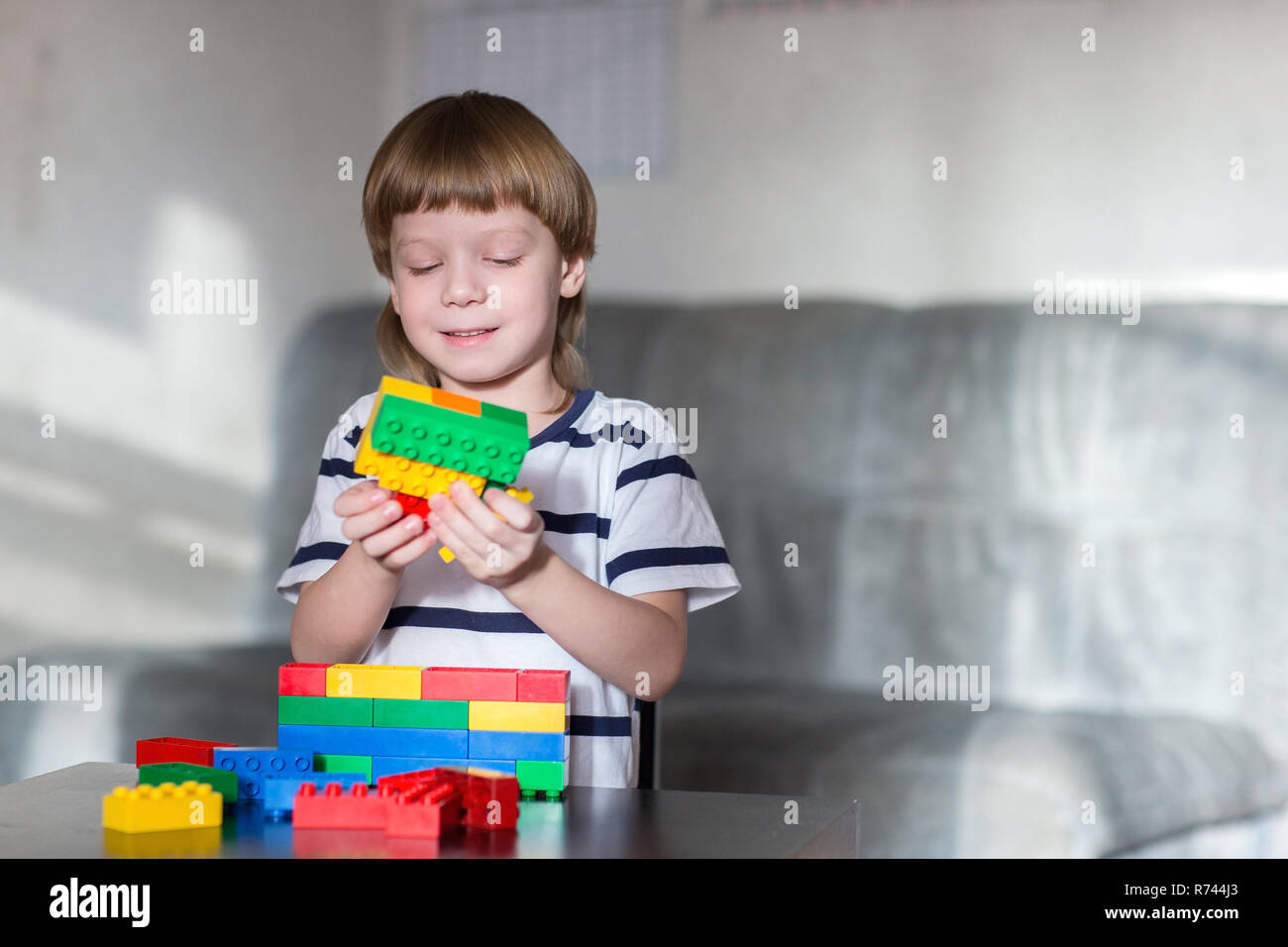 Little kid boy playing with lots of colorful plastic blocks indoor ...
